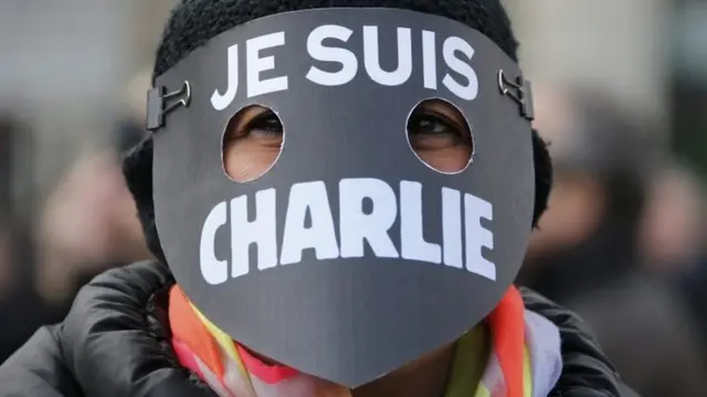 Une femme portant un masque et lisant "Je suis Charlie".