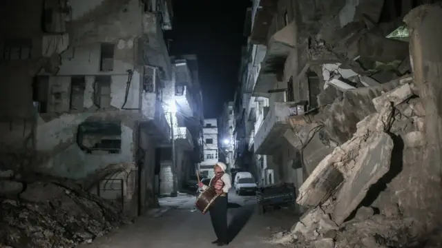 یک نوازنده طبل ماه رمضان در میان خانه‌های ویران شده در ادلب سوریه برای سحر مسلمانان را بیدار می‌کند