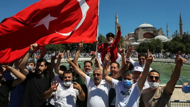 A man waves a Turkish flag as people gather around the Hagia Sophia Mosque ahead of Friday prayer, performed for the first time in 86 years on July 24, 2020 in Istanbul