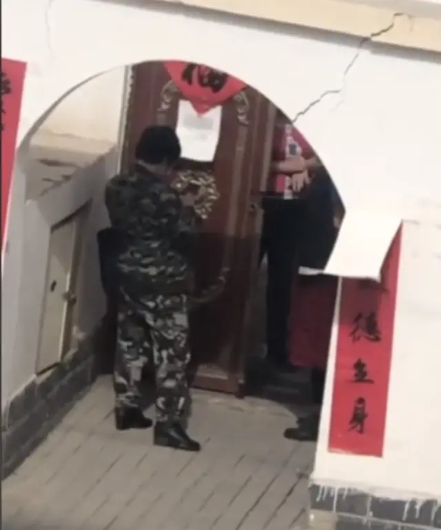 阿巴的视频中有身穿迷彩服的男子负责在院口守卫。