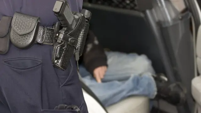 Un joven dentro de una patrulla de policía