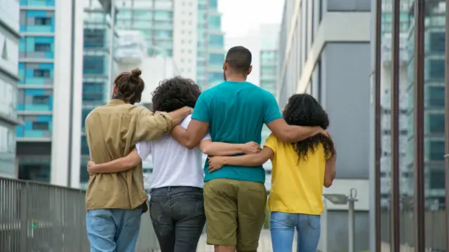 Cuatro personas caminan abrazadas.