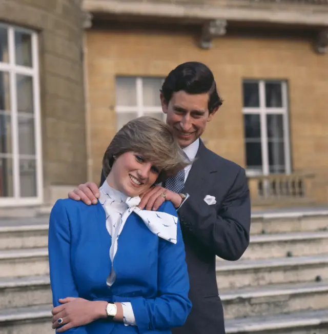 Rei Charles 3º e sua noiva, Lady Diana Spencer, na área externa do Buckingham Palace, após o anúncio do noivado, em 24 de fevereiro de 1981