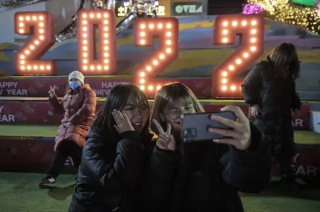 New Year"s Eve celebrations in Beijing 31/12/2021 European Pressphoto Agency epa09661593 People pose for selfies in front of a 2022 decoration outside a shopping complex to celebrate the upcoming new year 2022 in Beijing, China, 31 December 2021. Many cities in China canceled New Year"s Eve celebrations amid rising concerns over the coronavirus disease (COVID-19) pandemic. EPA/WU HONG