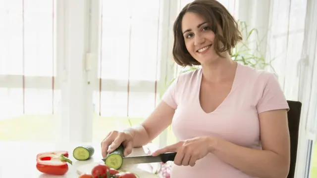 Une femme enceinte souriante prépare un déjeuner sain.