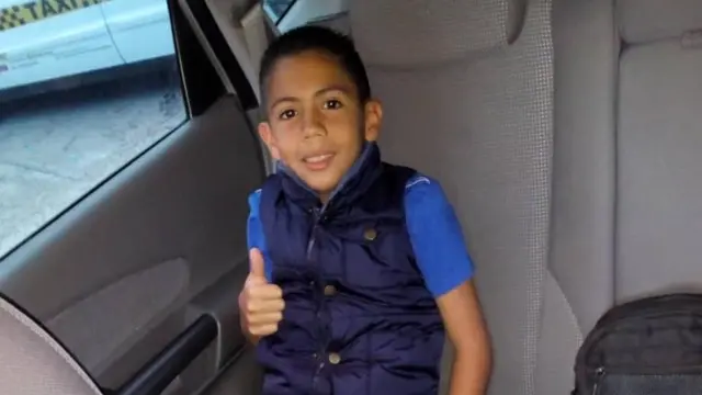 Brayan sonriendo dentro de su carro familiar