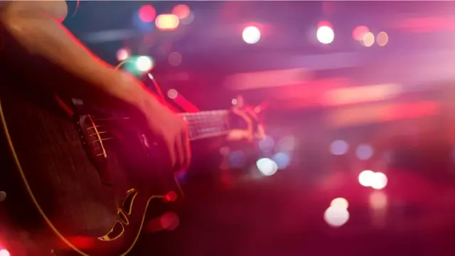 Hombre tocando una guitarra en el escenario.
