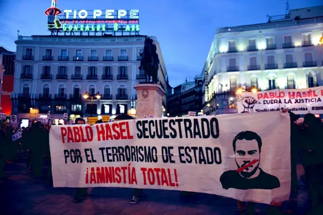 متظاهرون يحملون لافتة عليها صورة بابلو التي تعبر عن قمع التعبير