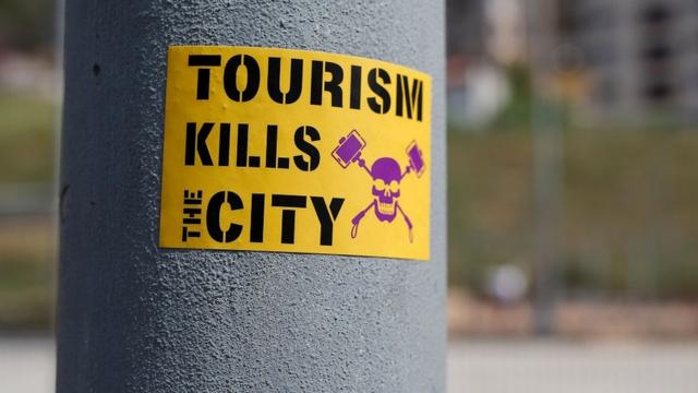 西班牙巴塞罗那一个电灯杆上贴出的反旅游业标语：旅游扼杀城市。