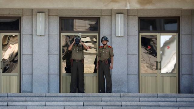 A North Korean soldier keeps watch toward the south through a binocular telescope at the truce village of Panmunjom, South Korea on 26 August