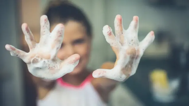 Menina com as mãos ensaboadas