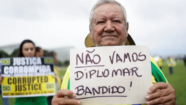 Senhor segurando cartaz que diz: Não vamos diplomar bandido