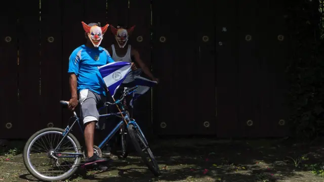 Dos jóvenes con máscaras de payaso y banderas de Nicaragua