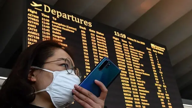 Uma passageira usando uma máscara falaqual o melhor casa de apostaseu smartphone pelo quadroqual o melhor casa de apostapartidas