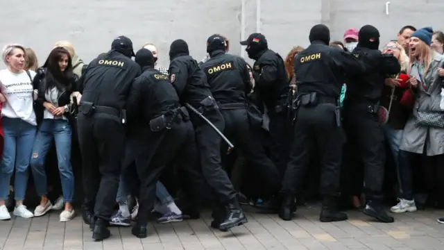 Riot police grab people in order to detain them, from a crowd of women on 8 September