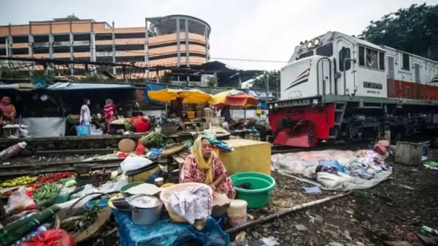 Sebuah kereta melintasi rel yang kiri-kanannya dipenuhi pedagang di Surabaya, Jawa Timur, Februari 2017.