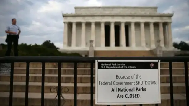 One man stand in front of one building wey dem put notice of shutdown of national parks