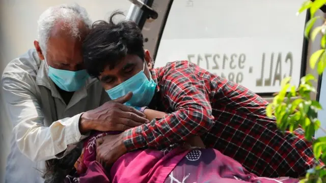 Two men crying as they hold a relative's body