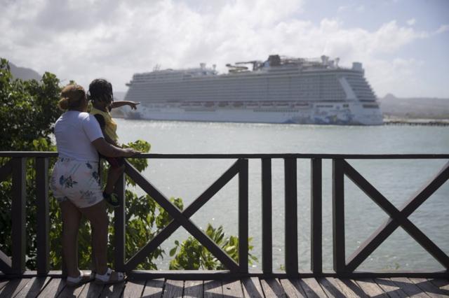 Una mujer y un menor observan el crucero Norwegian Escape en el puerto de Taino Bay, en Puerto Plata, República Dominicana, el 15 de marzo de 2022.