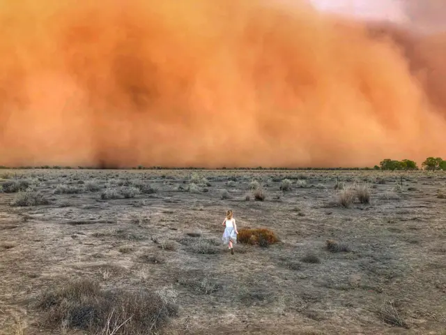 A child running towards a dust storm in Mullengudgery in New South Wales - Wani dan yaro yana gudu ta inda guguwar Mullengudgery yake a New South Wales.