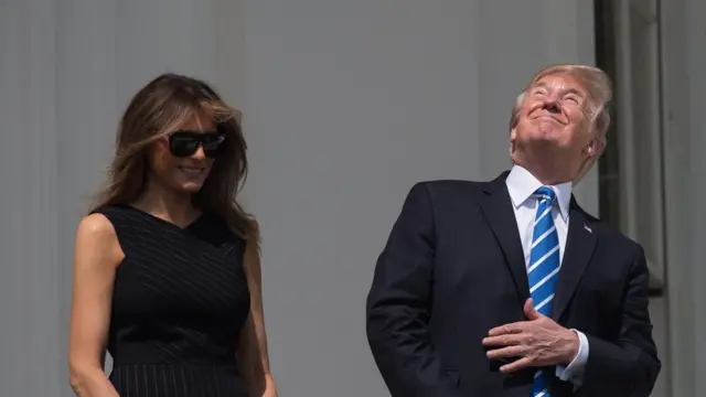 US President Donald Trump, with First Lady Melania Trump at his side, looks up at the partial solar eclipse from the balcony of the White House in Washington, DC, on August 21, 2017