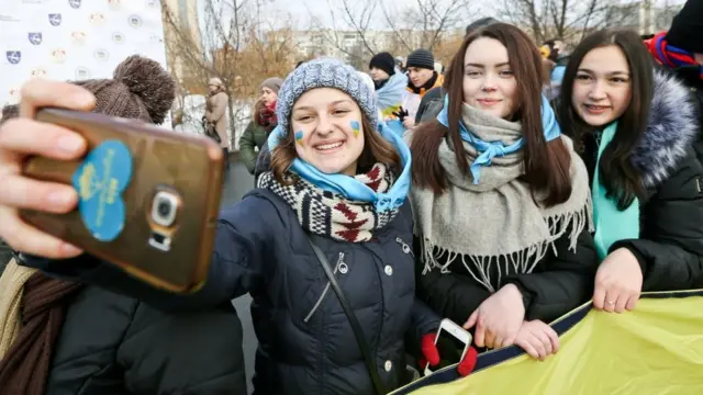 З обох берегів Дніпра колони людей принесли синю і жовту стрічки і розгорнули на мосту 30-метровий прапор України