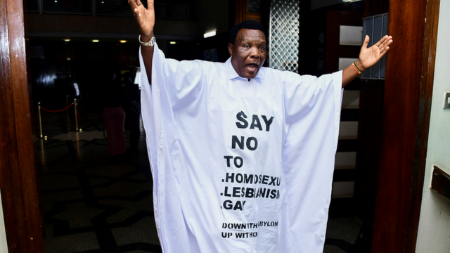 Le député ougandais John Musira, vêtu d'une robe anti-gay, fait un geste alors qu'il quitte les chambres pendant le débat sur le projet de loi anti-homosexualité.