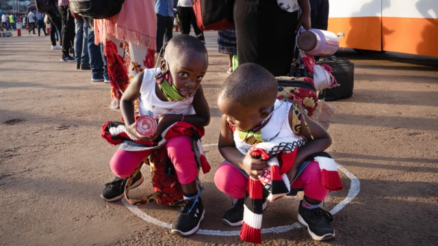 Children in face masks crouch in white circles put at bus stations to ensure social distancing in Kigali, Rwanda -4 May 2020
