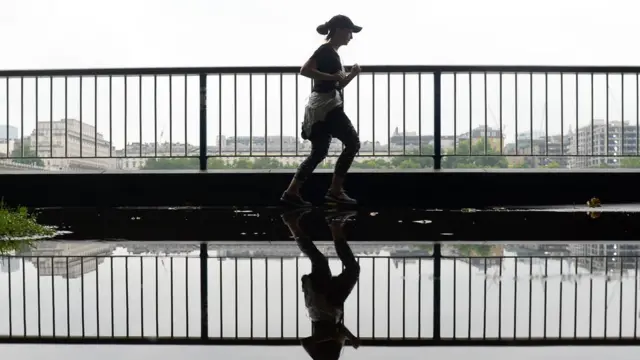 A woman runs through a puddle on the South Bank in London