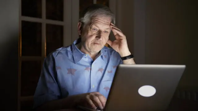 Señor mayor mirando una computadora.