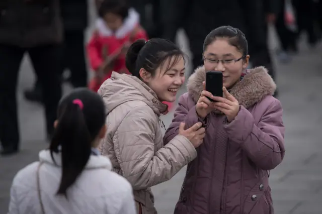 प्योंगयांग में मोबाइल पर कुछ देखती हुई लड़कियां