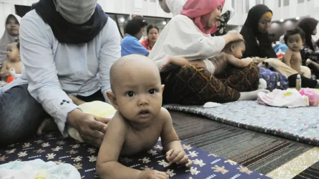 Women massage babies in a large hall