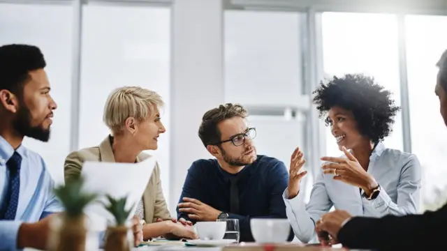 Cinco pessoas sentadas à mesa durante reuniãosaque arbetyescritório