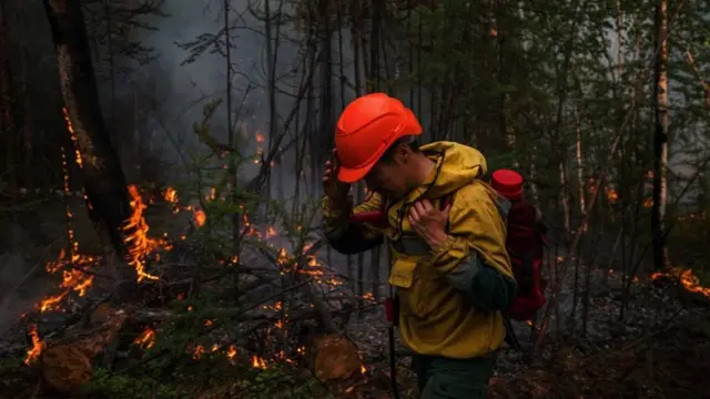 A member of Aerial Forest Protection Service monitors a backfire in Siberia on July 26. 2021