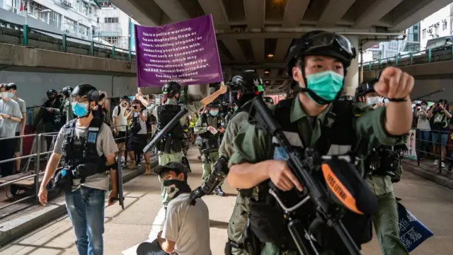 2020年7月1日,香港國安法實行翌日,多名警員在街員,一名警員舉著一幅紫色的國安警告旗幟。