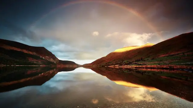 Arco iris de un lado a otro de la montaña