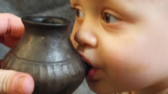 جدید عہد کا ایک بچہ قدیم زمانے کے لوٹا نما برتن کی طرز پر پھر سے بنائے گئے برتن سے دودھ پیتے ہوئے