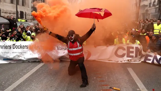 Un manifestant tient une torche de fumée lors d'une manifestation contre la réforme des retraites à Marseille, France, le 5 décembre 2019