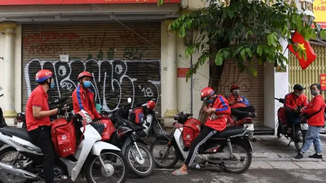 Shipper chờ đơn hàng dọc một con phố ở Hà Nội vào ngày 25 tháng 5 năm 2021 khi chính quyền mở rộng lệnh đóng cửa để ngăn chặn sự lây lan của coronavirus Covid-19 (ảnh minh họa)