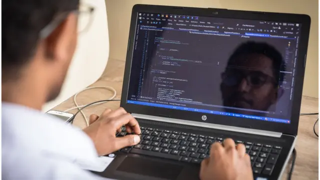 ላብ ቶፕ ኮምፒውተሩ ላይ የሚሰራ ወጣት