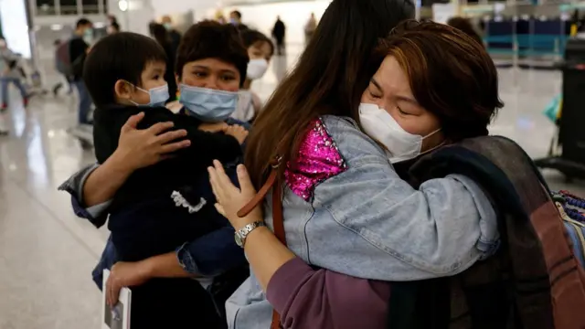香港国际机场一号客运大楼离境大堂一女士在禁区入口前与即将飞往英国定居的亲属拥抱话别（17/12/2020）