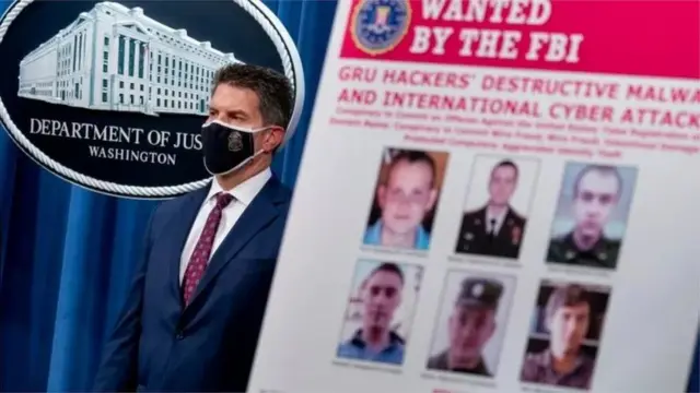 યુએસમાં એફબીઆઈ અધિકારી રશિયન હેકરોનું પોસ્ટર બતાવે છે. ઑક્ટોબર 2020માં, યુએસએ દાવો કર્યો હતો કે આ તમામ લોકો રશિયન ગુપ્તચર એજન્સીનો ભાગ છે અને અન્યમાં હેકિંગમાં સામેલ રહ્યા છે.