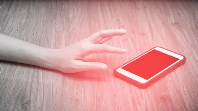 Una mano alcanzando un teléfono en el suelo