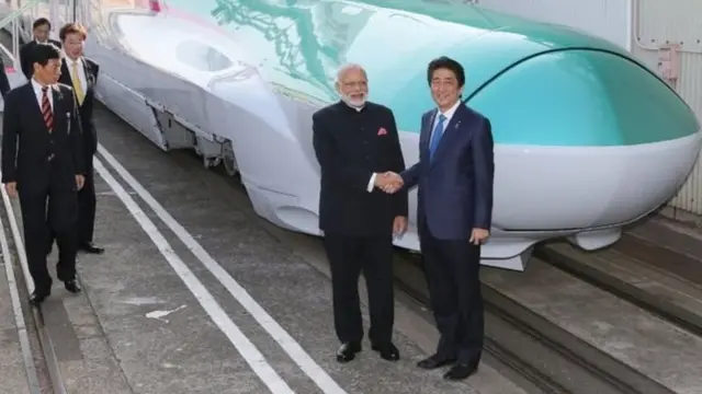 बुलेट ट्रेन के आगे हाथ मिलाते मोदी