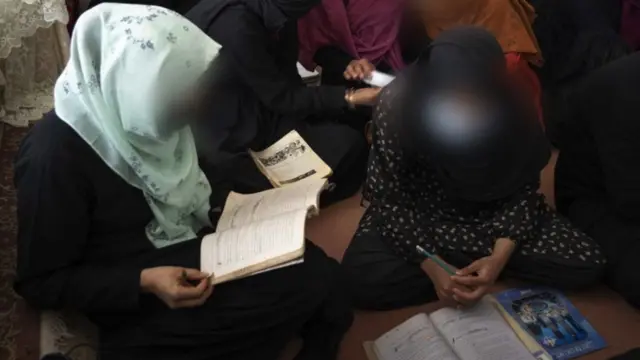 La bibliothèque de près de 20 jeunes femmes réunies dans une salle de classe informelle.