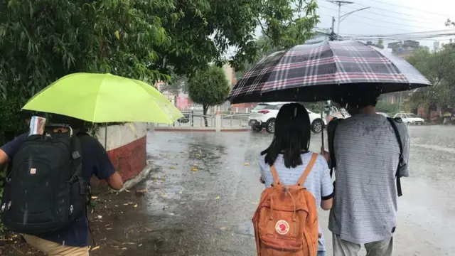 काठमाण्डूमा झरी परेपछि छाता ओढ्दै हिँडेका युवा युवती