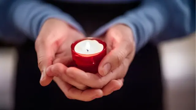 Mãos unidas segurando vela
