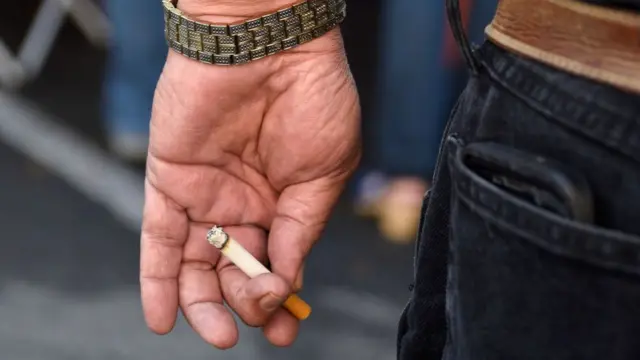 Homem segura cigarro na mão