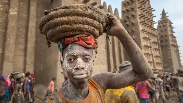 Un homme à Djenné, au Mali, participe au Crépissage à la Grande Mosquée
