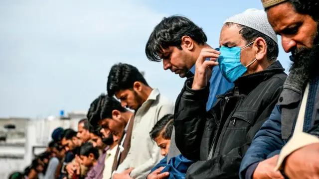 پاکستان کے شہر راولپنڈی میں 13 مارچ 2020 کو نماز کی ادائیگی کے دوران ایک شخص کورونا وائرس سے بچنے کے لیے ماسک پہنے ہوئے ہے